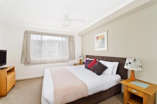 een slaapkamer met een groot bed en een televisie bij Beach Resort Apartment in Port Macquarie