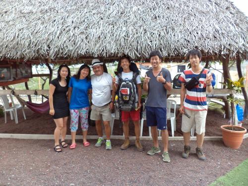 a group of people standing in front of a thatch hut at Posada del Caminante in Puerto Villamil