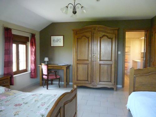 a bedroom with a bed and a wooden cabinet at L'orchidée in Rochehaut