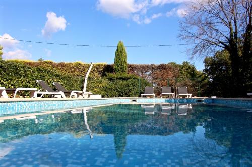 ein Schwimmbad mit einem Haufen Stühle drum herum in der Unterkunft Hotel Les Oliviers in Draguignan