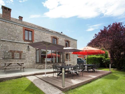 a patio with tables and chairs and umbrellas at Spacious Holiday Home in Humain with Garden in Marche-en-Famenne