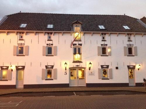 Un grand bâtiment blanc avec des lumières dans les fenêtres dans l'établissement Hotel De Gravin, à s-Gravenzande