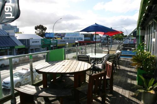 een patio met tafels en stoelen en een parasol bij Backpackers Central Hamilton in Hamilton