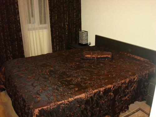 a bed with a brown bedspread with a purse on it at Отель Гармония in Dnipro