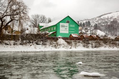 ラーヒフにあるDream Hostel Carpathians Rakhivの雪川の横の緑の建物