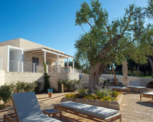 eine Terrasse mit Stühlen und einem Baum vor einem Haus in der Unterkunft Borgo de li Santi in Otranto