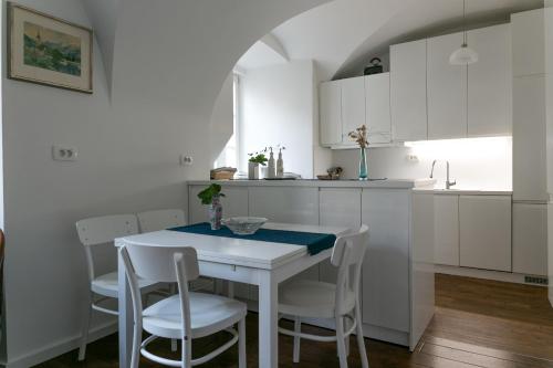 a kitchen with white cabinets and a white table and chairs at 3 Bridges App in Ljubljana