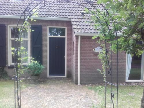 una casa in mattoni con una porta nera e una finestra di De Oude Smederij a Noord-Sleen