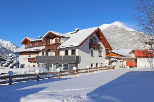 een huis in de sneeuw met bergen op de achtergrond bij Appartementhotel Zugspitzhof in Ehrwald