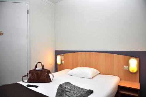 una habitación de hotel con una cama con un bolso en Premiere Classe Niort Est - Chauray, en Niort