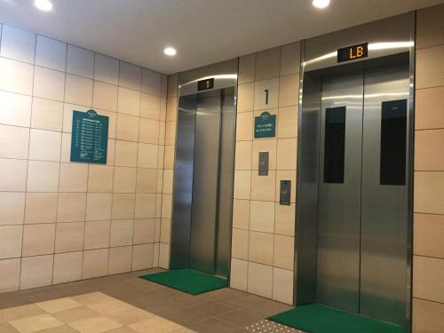 dois elevadores numa estação de metro com tapetes verdes em Sotetsu Fresa Inn Fujisawa Shonandai em Fujisawa