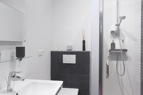 La salle de bains blanche est pourvue d'un lavabo et d'une douche. dans l'établissement B&B Villa 36, à Bruxelles