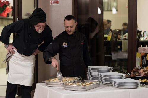 Dois chefs em frente a uma mesa com comida. em Pridvorul Haiducilor em Slănic-Moldova