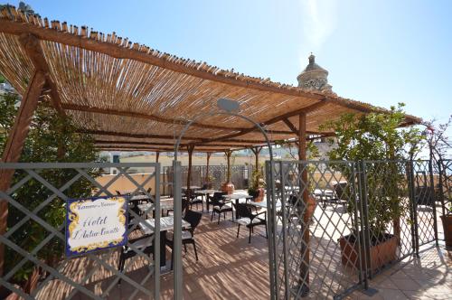 una pérgola con mesas y sillas en un patio en Albergo L'Antico Convitto, en Amalfi