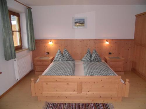 una camera con letto in legno e cuscini blu di Appartements Färberhof a Valdaora