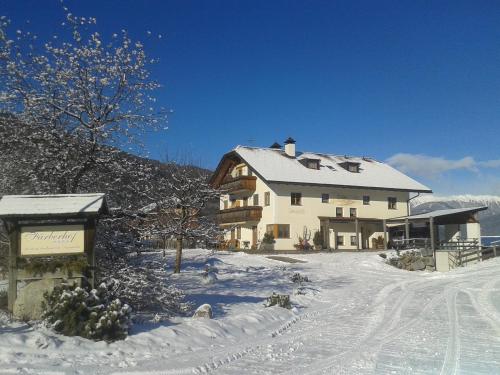 una grande casa bianca nella neve con la neve di Appartements Färberhof a Valdaora