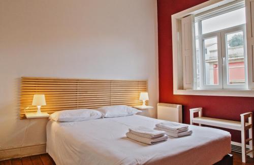 Un dormitorio con una cama con paredes rojas y una ventana en Porto Spot Hostel, en Oporto