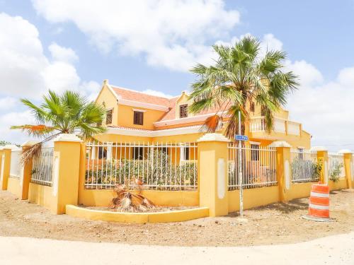 una casa amarilla con palmeras delante en Landhuis Belnem Bonaire, en Kralendijk