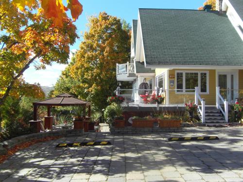 une maison avec une terrasse en face de celle-ci dans l'établissement Gîte Au Perchoir, à Baie-Saint-Paul