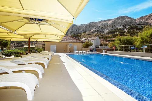 una piscina con sedie bianche e ombrelloni di Hotel Dobrovit a Baška