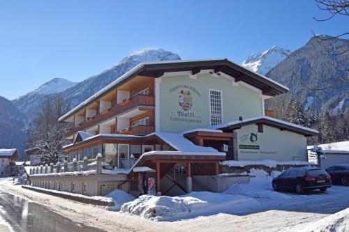 un grand bâtiment dans la neige avec des montagnes en arrière-plan dans l'établissement Gästehaus Waltl, à Krimml