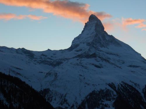 een met sneeuw bedekte berg met een zonsondergang op de achtergrond bij Chalet Kolibri in Zermatt