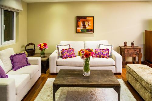 - un salon avec des canapés et un vase de fleurs sur une table dans l'établissement Apart-Hotel Casa Serena, à Guatemala