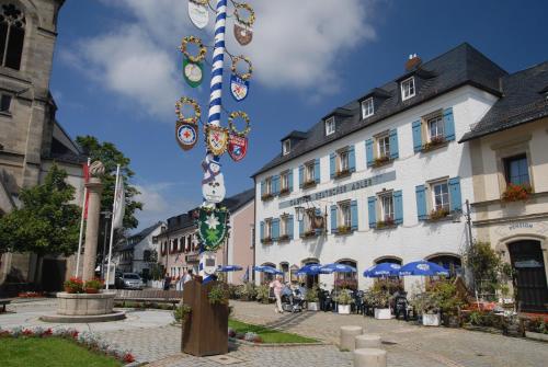 una calle con un edificio y un poste decorado en Gasthof Deutscher Adler und Hotel Puchtler, en Bischofsgrün