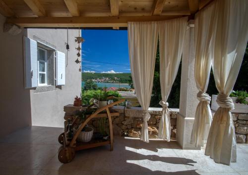 eine Veranda mit Vorhängen und Meerblick in der Unterkunft White Cottage Heritage House in Čižići