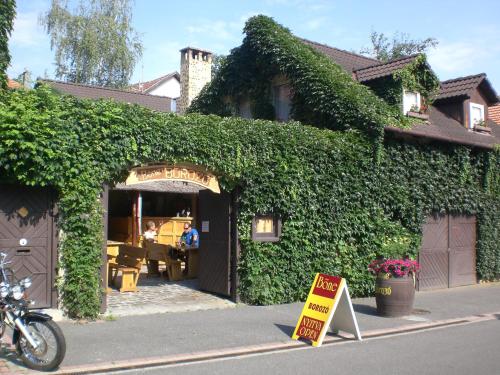 un bâtiment recouvert de lierre avec un panneau devant lui dans l'établissement Böne Vendégház és Borozó, à Tokaj