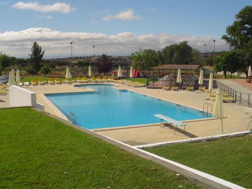 una grande piscina con sedie e ombrelloni di Hotel Rural Quinta de Santo Antonio a Elvas