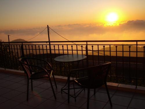 a table and chairs on a balcony with the sunset at Zephyros Rooms And Apartments in Drymon