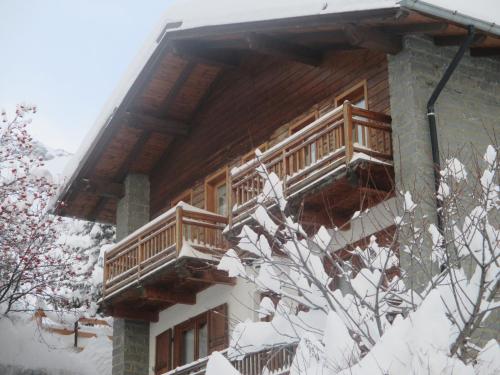 a log cabin with two decks in the snow at Hotel Le Clocher in Champoluc