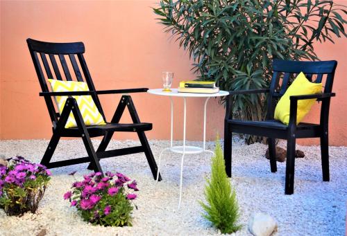 twee stoelen en een tafel in een tuin met bloemen bij Casa Vacanze Mura in Cala Gonone