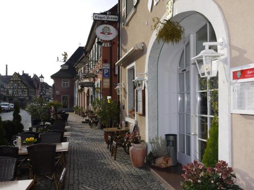 eine Straße mit Tischen und Stühlen und eine Uhr auf einem Gebäude in der Unterkunft Hotel Engel in Endingen