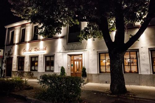 een wit gebouw met een boom ervoor bij Gasthof Roderich Hotel in Langenzersdorf