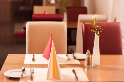 a wooden table with plates and napkins and a vase with a flower at Hotel Dietrichsdorfer Hof in Kiel