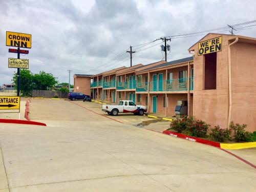 una strada vuota con un edificio con un cartello sopra di Crown Inn Grand Prairie a Grand Prairie