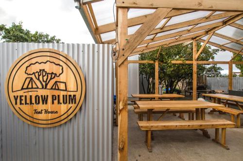 un panneau indiquant un restaurant de prunes jaunes à côté des tables en bois dans l'établissement Camping Yellow Plum, à Puerto Natales