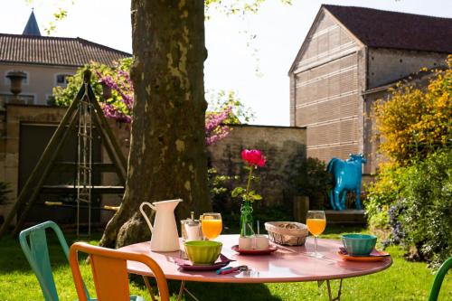 un tavolo rosa con sopra delle bevande in cortile di Le Clos de l'Abbaye a Cluny