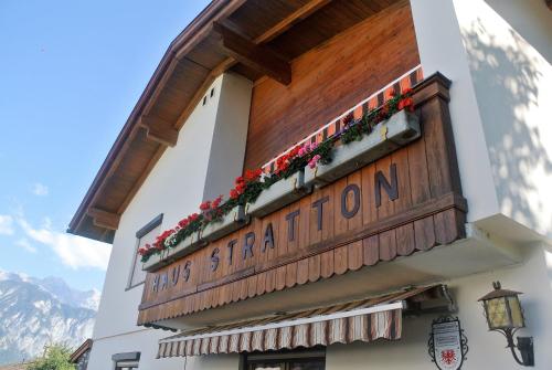 un panneau sur le côté d'un bâtiment avec des fleurs dans l'établissement Haus Stratton, à Innsbruck