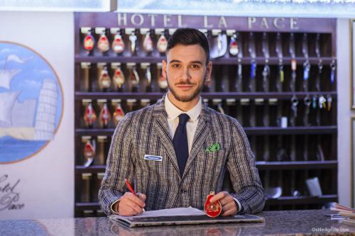 a man standing at a counter holding a pen at Hotel La Pace in Pisa