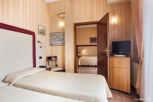 a hotel room with two beds and a television at Hotel La Pace in Pisa