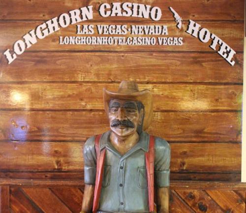 een standbeeld van een man met een cowboyhoed op een muur bij Longhorn Boulder Highway in Las Vegas