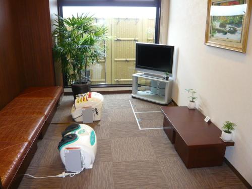 een woonkamer met een bank en een flatscreen-tv bij Hotel Route-Inn Koriyama Minami in Koriyama