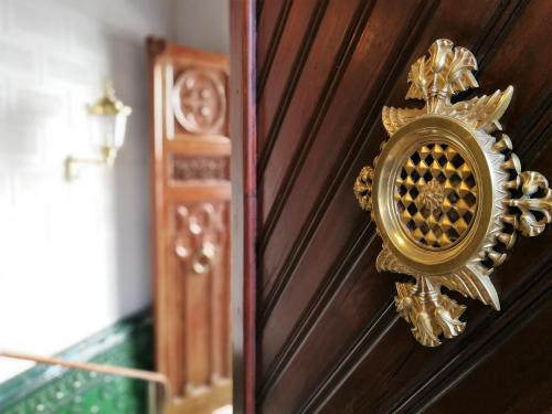 a gold door knocker on a wooden wall at Hotel El Xalet in Sitges