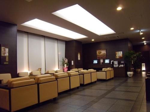 une salle d'attente avec une rangée de chaises et une lucarne dans l'établissement Hotel Route-Inn Tsuruoka Ekimae, à Tsuruoka