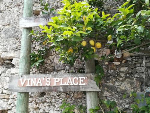 a sign in front of a wall with a lemon tree at Vina's Place in Nazaré