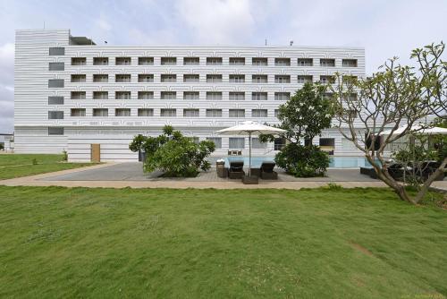 un grand bâtiment blanc avec une pelouse devant lui dans l'établissement Hotel Naveen Lakeside, à Hubli