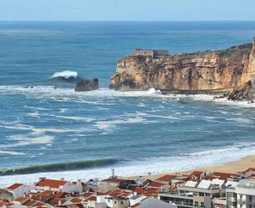 uma vista para uma praia com um castelo sobre um penhasco em Hospedaria A Primorosa na Nazaré